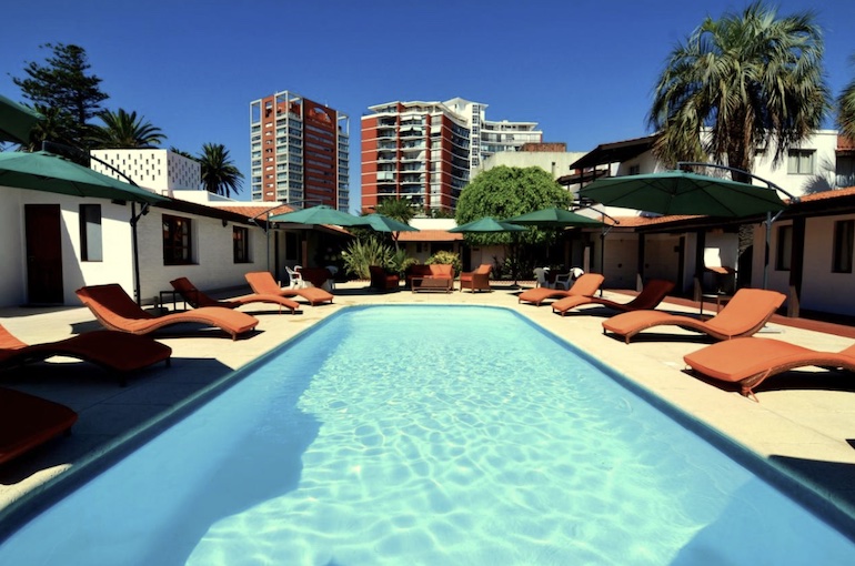 Cadeiras e guarda-sol ao redor da piscina de hotel barato em Punta del Este